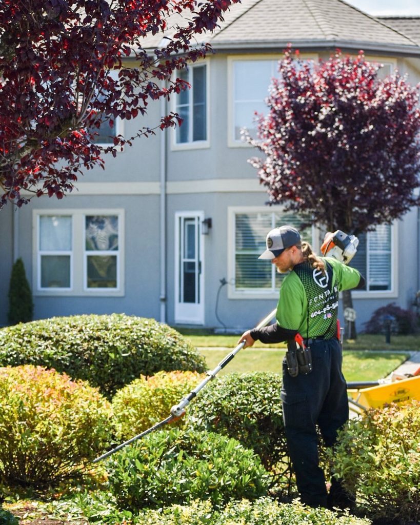 A man using a lawn mower in front of a house.