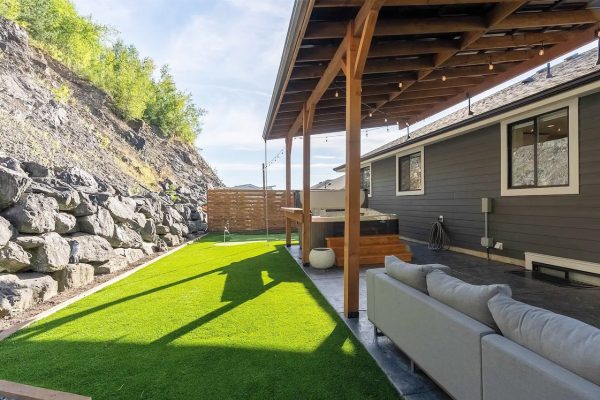 A backyard with artificial grass and a rock wall.