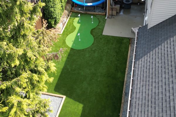 A backyard with artificial grass and a trampoline.